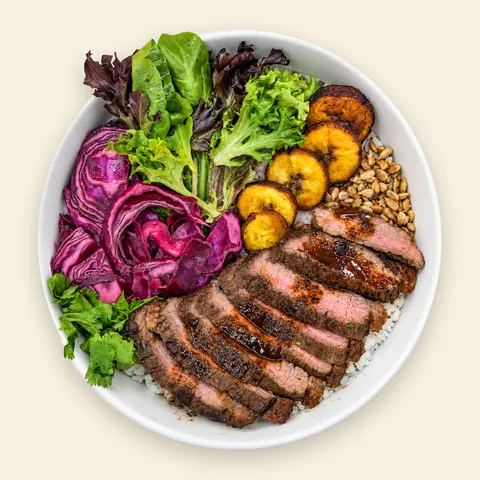 VIVA Caribbean Plantain Beef Bowl from VIVA Bowls Miami, seen from above: seasoned beef over herb jasmine rice and fresh greens with caramelized sweet plantain and tangy pickled cabbage
