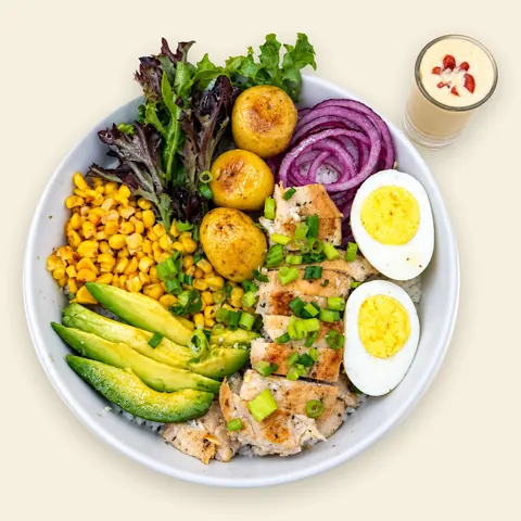 VIVA Farmhouse Farmhouse Chicken Bowl from VIVA Bowls Miami, seen from above: peppery arugula with grilled chicken, golden papa criolla, creamy avocado, sweet corn and egg