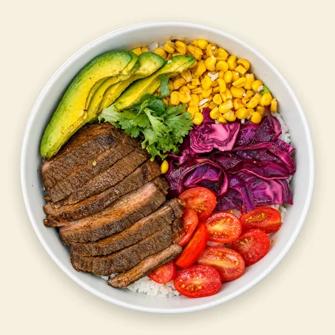 VIVA Mexican Mexican Beef Bowl from VIVA Bowls Miami, seen from above: seasoned beef over herb jasmine rice with creamy avocado, roasted corn, fresh tomato and crunchy cabbage